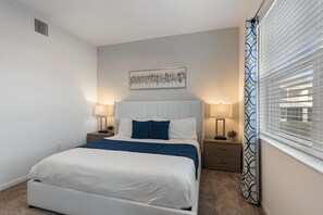 A bedroom with a bed, two bedside tables, a wall-mounted artwork, and a window with blinds. - The Splash Shot -Championsgate Resort, Amenities Included/Games Room/Free wifi (Kissimmee)