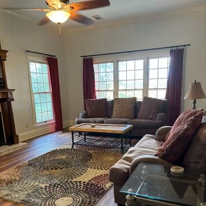 A living room with a sofa, coffee table, patterned rug, and a ceiling fan. - Southern Comfort with plenty of room for the entire family. (Byhalia)