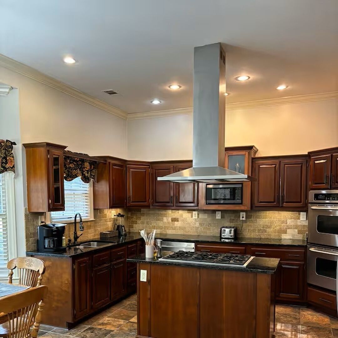 A kitchen with wooden cabinets, a central island, a microwave, and a stove.