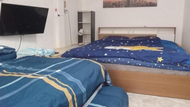 Makuuhuone, jossa on sänky, seinälle asennettu televisio ja sängyn yläpuolella oleva taulu.