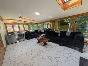 A living room with a sectional sofa, a coffee table, and a washing machine. - The Lodge at South of the Border (Canaan)