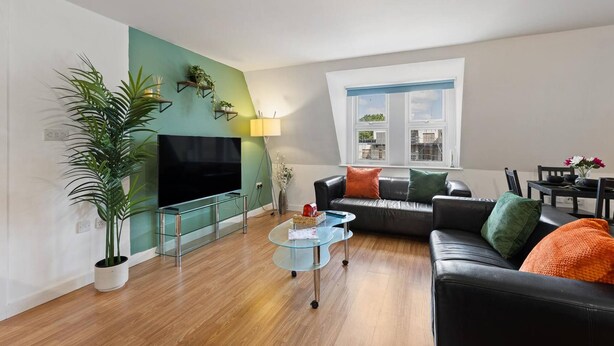 A modern living room with a flat-screen TV, a glass coffee table, a leather sofa, and a potted plant. - West Bridgford Luxury 2 bed 2 Bath Apartment (Nottingham)