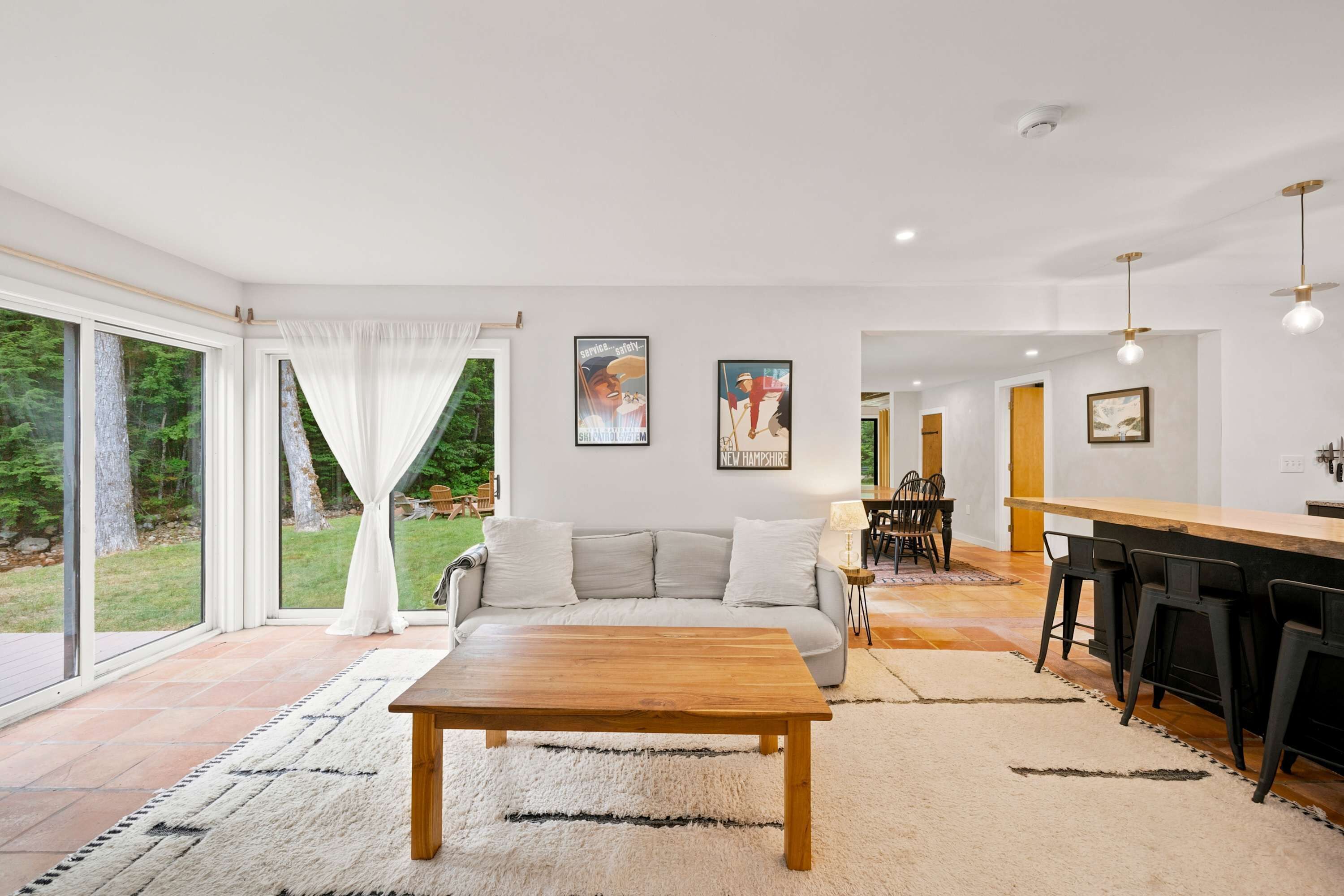 A modern living room with a sofa, a wooden coffee table, and a kitchen area with bar stools.
