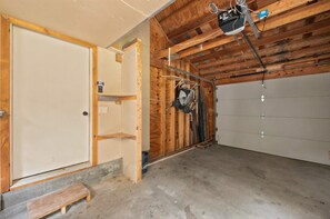 Un garage avec un plafond en bois, une porte blanche et un sol en béton.