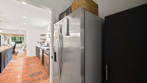 Een moderne keuken met een roestvrijstalen koelkast, een donker kastje en een gevlochten mand erop.