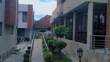 A courtyard with a pathway, a seating area, and a lamp post.