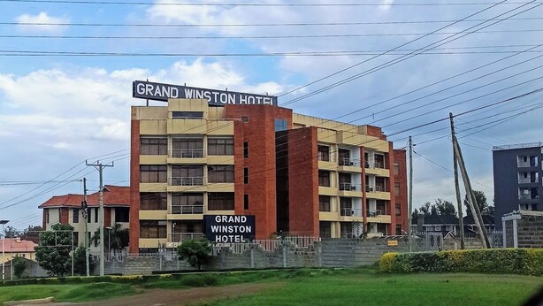 Un hotel de varios pisos con un letrero llamativo que dice 'Grand Winston Hotel'.
