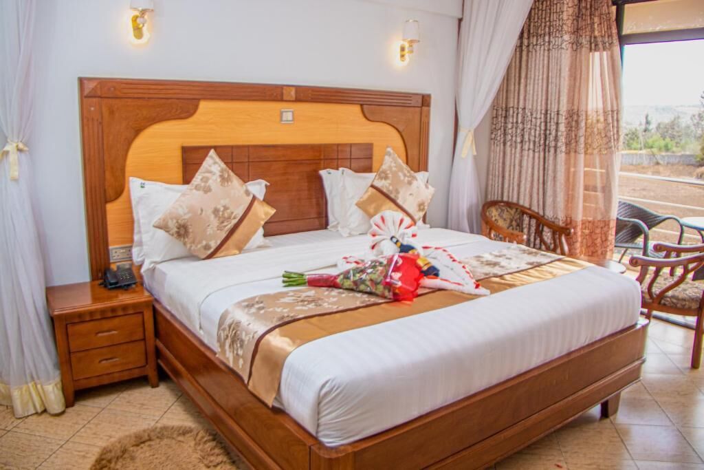 A neatly made bed with a wooden headboard, a bedside table with a phone, and a chair.