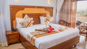 A neatly made bed with a wooden headboard, a bedside table with a phone, and a chair.