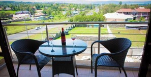 A balcony with a table and chairs, a bottle of wine, and wine glasses. - Grand Winston Hotel (Nakuru)
