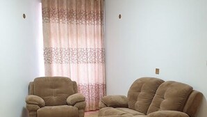 Una sala de estar con un conjunto de sofá, una mesa de centro y una cortina estampada.