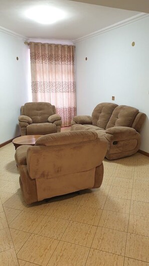 A living room with a sofa set, a coffee table, and a patterned curtain.