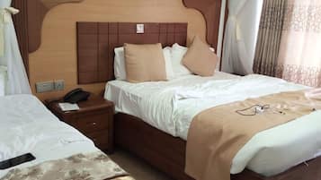 A hotel room with a large bed, bedside tables, a telephone, and a bedside lamp.
