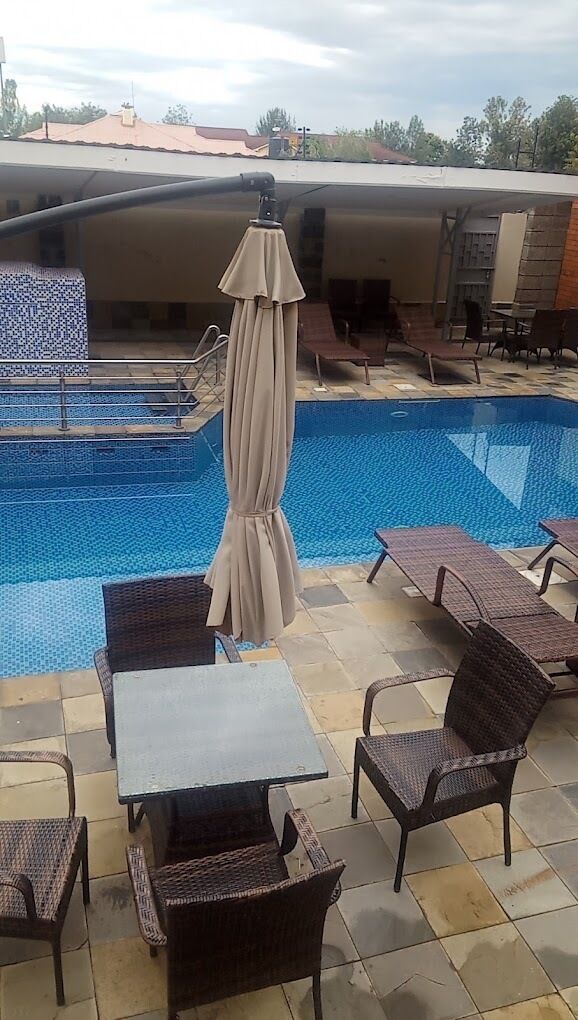 Zona de piscina con sillas de descanso, una mesa y un toldo.