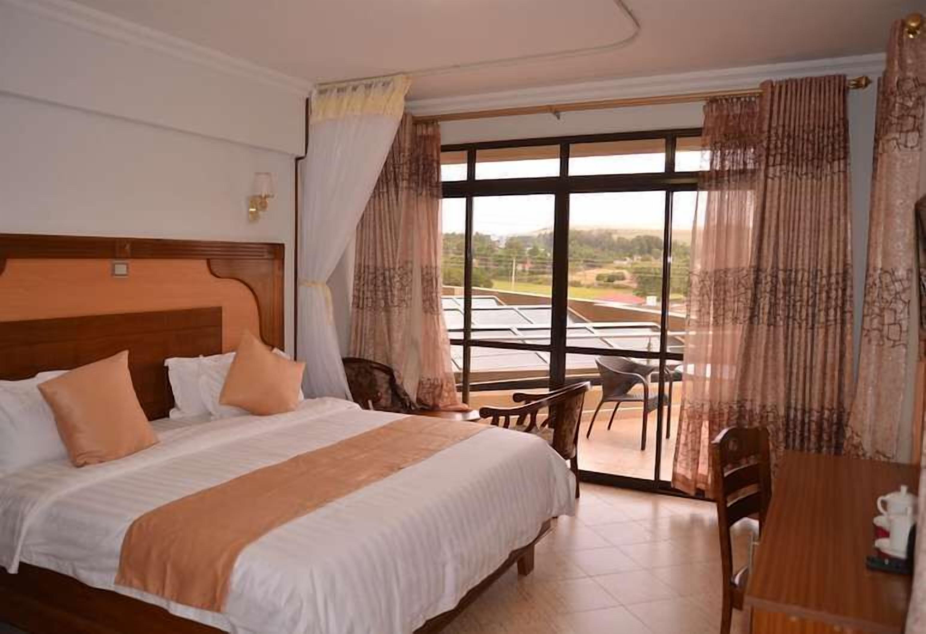 A hotel room with a large bed, a dining table, and a view of the outdoors.