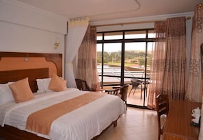 A hotel room with a large bed, a dining table, and a view of the outdoors.