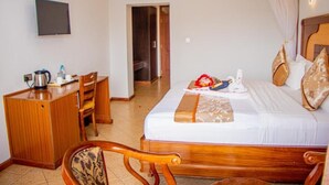 Una habitación de hotel con una cama, un escritorio, una silla y un televisor en la pared.
