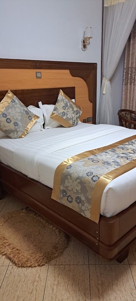 A neatly made bed with a wooden headboard, a decorative bedspread, and matching pillows.