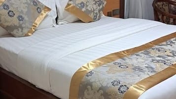 A neatly made bed with a wooden headboard, a decorative bedspread, and matching pillows.