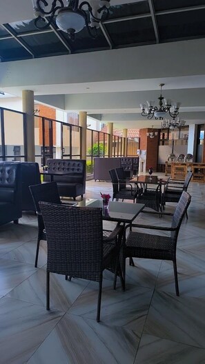 A spacious indoor area with modern furniture, including sofas and dining tables, and a ceiling with decorative elements.
