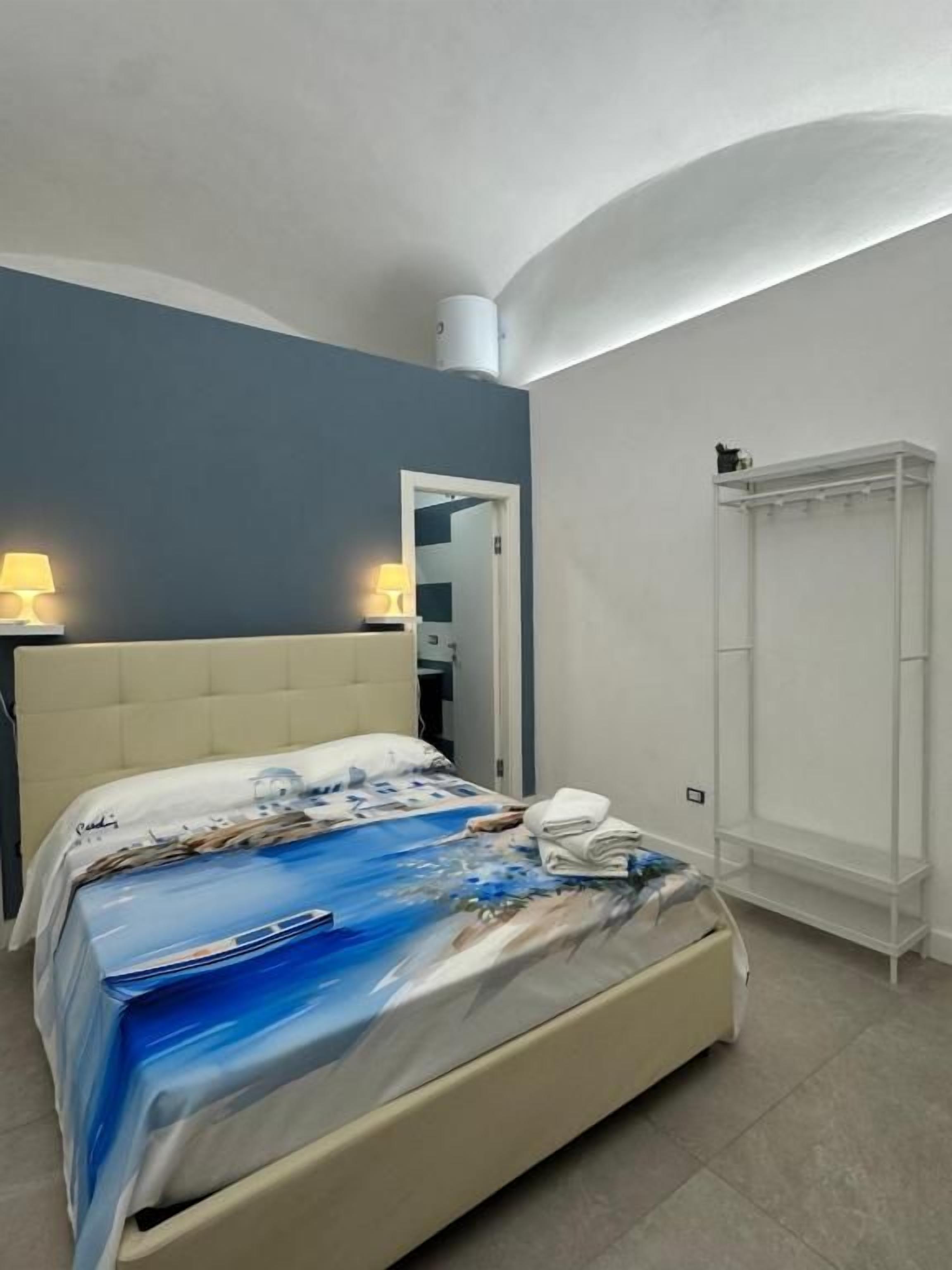A bedroom with a bed, bedside lamps, a wardrobe, and a bathroom door.