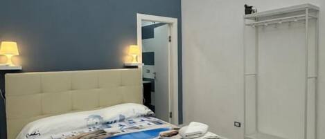 Et soveværelse med seng, sengeborde, en garderobe og dør til badeværelse.