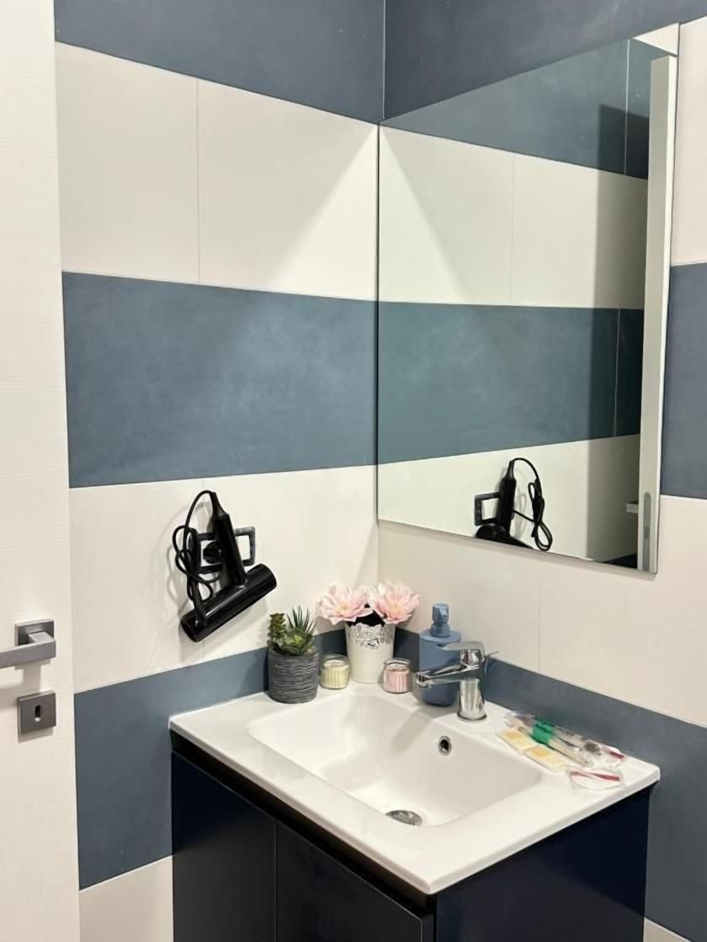 A bathroom with a white sink, a mirror, and a towel rack.