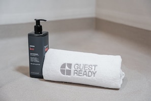 A bottle of shampoo and a towel with 'GUEST READY' embroidered on it. - GuestReady - Studio near Porto Universities (São Mamede de Infesta)
