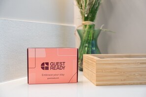 Eine rosafarbene Schachtel mit dem Aufdruck 'GUEST READY' und einer Website-Adresse.