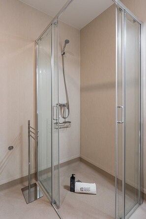 A glass-enclosed shower area with a handheld showerhead and a towel rack. - GuestReady - Studio near Porto Universities (São Mamede de Infesta)