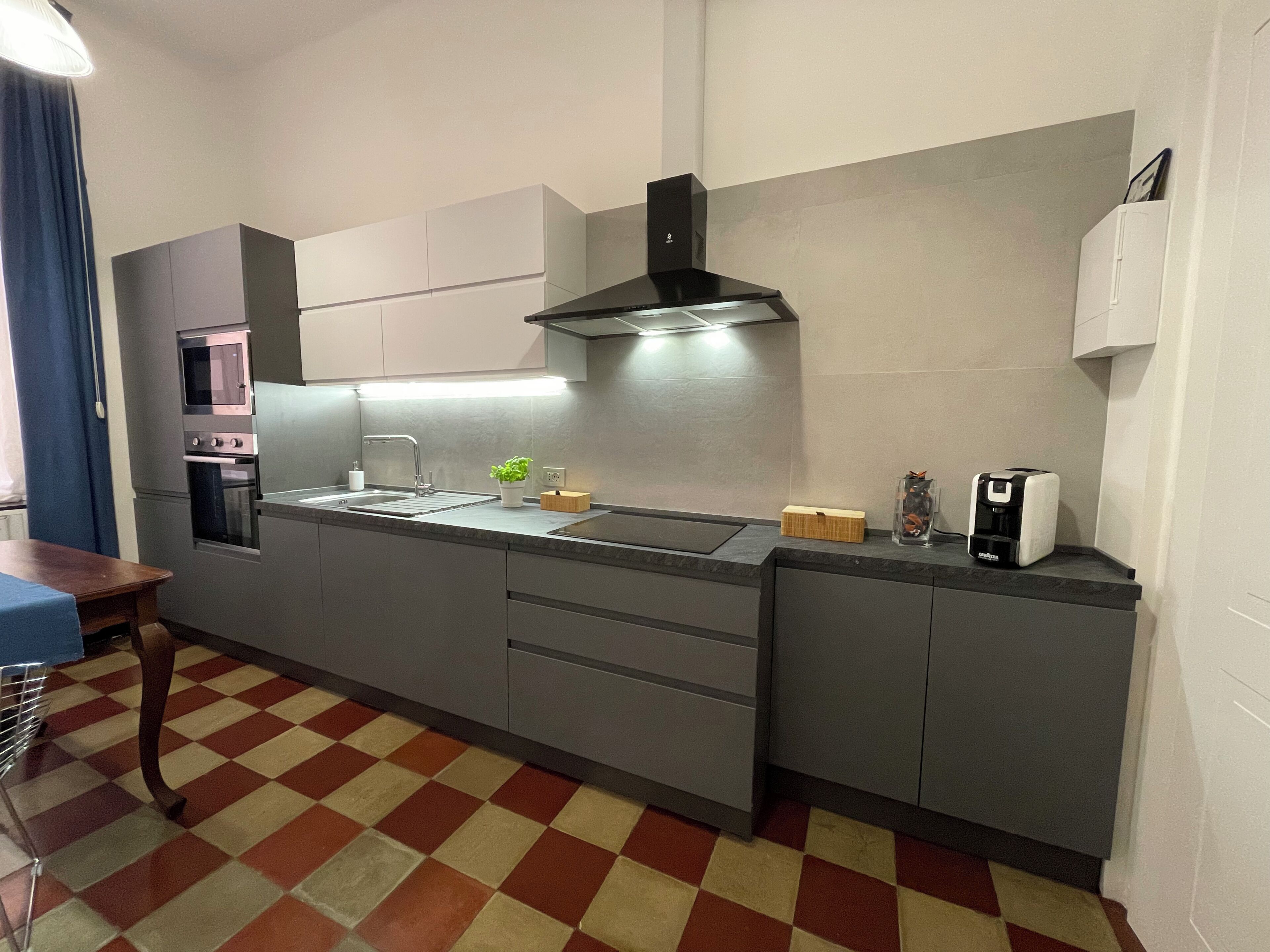 Una cucina moderna con forno integrato, lavello in acciaio inossidabile e microonde.