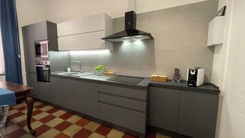 Una cucina moderna con forno integrato, lavello in acciaio inossidabile e microonde.