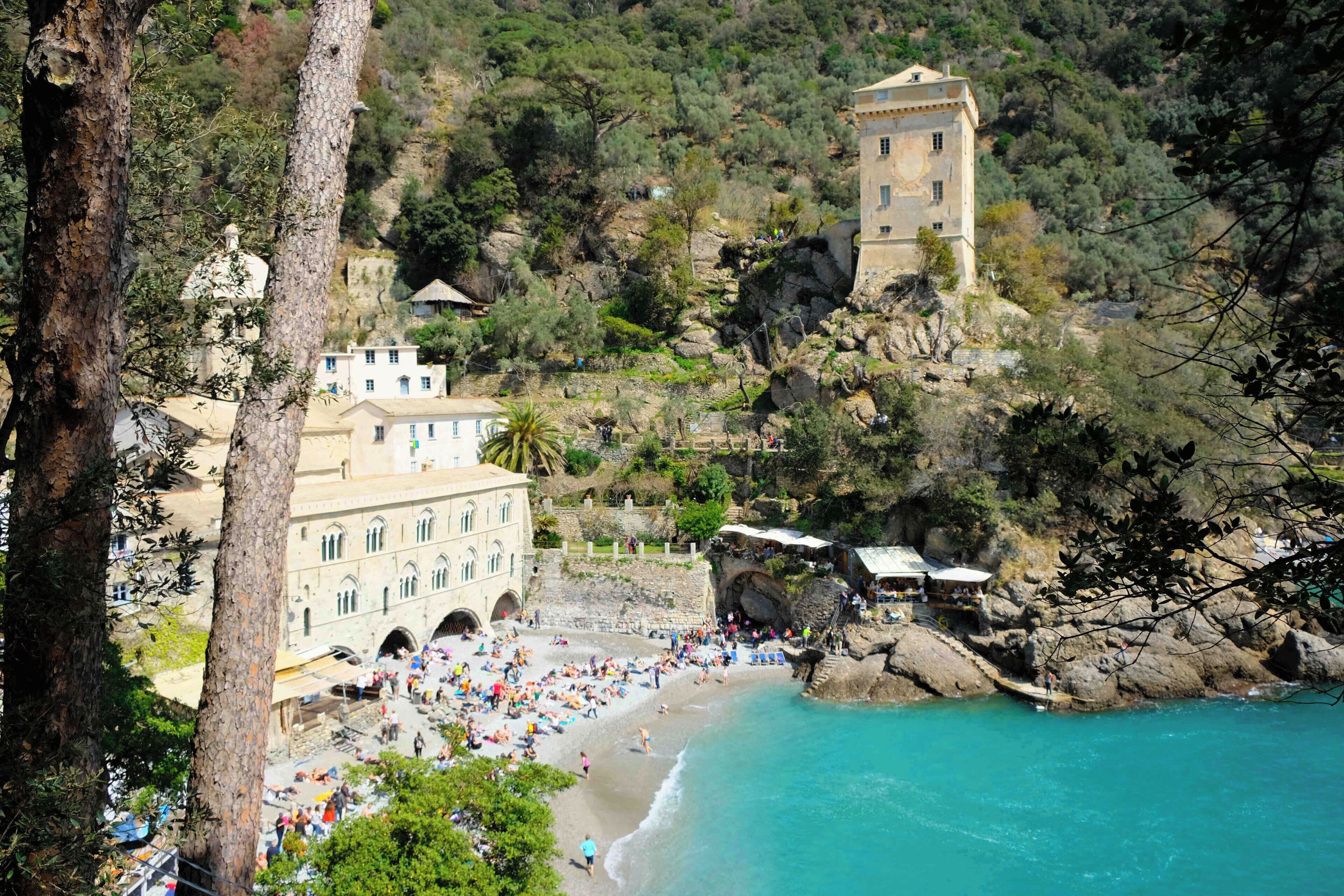 Una cittadina costiera con spiaggia, edifici storici e una torre.