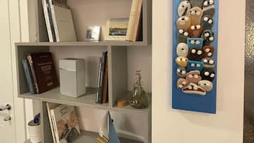 Una libreria con libri, un quadro incorniciato e un elemento decorativo a parete.
