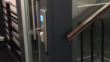 Un ascensore moderno con porta in vetro, display digitale e corrimano in metallo.