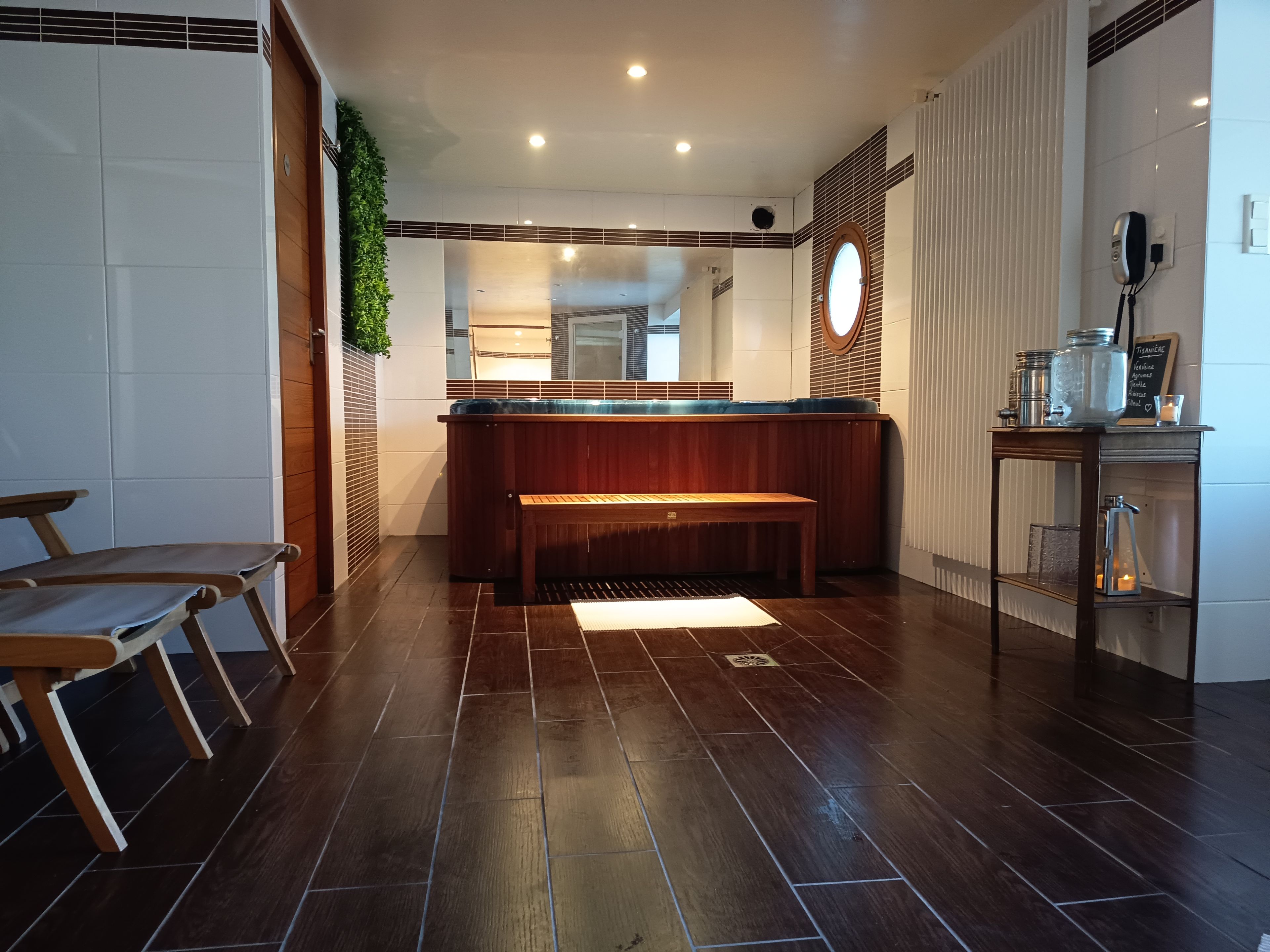 En modern hotellobby med en receptionsdisk i trä, en bänk och ett litet bord med burkar och ett ljus.