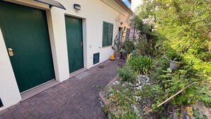 A narrow alleyway with two green doors, a potted plant, and a small garden area. - Callistemo Apartment (Rio)