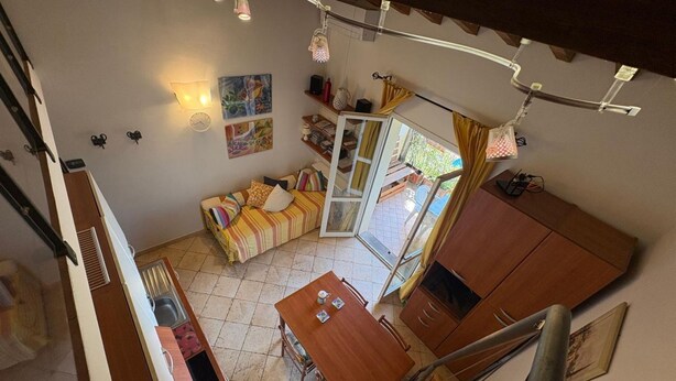 A compact living space with a dining area, a sofa, and a staircase. - Callistemo Apartment (Rio)
