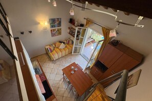 A compact living space with a dining area, a sofa, and a staircase. - Callistemo Apartment (Rio)