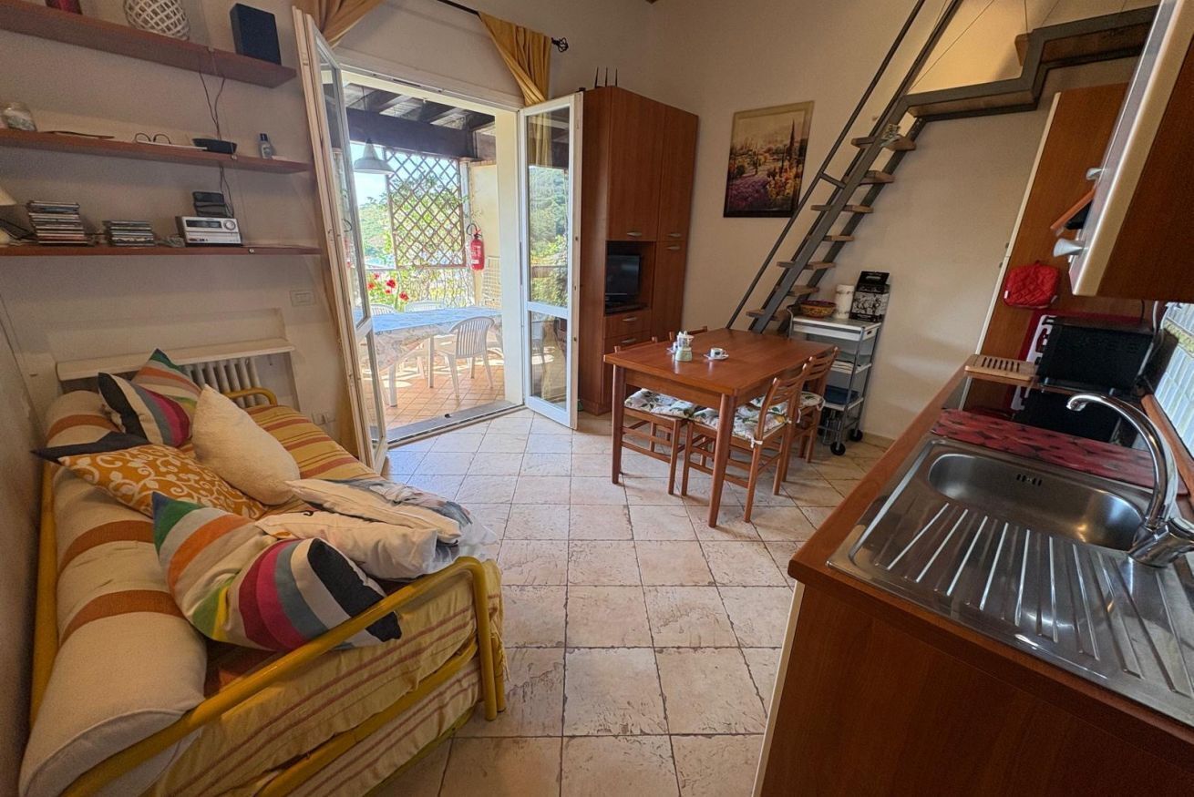 Een functionele ruimte met een bed, kitchenette, eettafel en een trap.