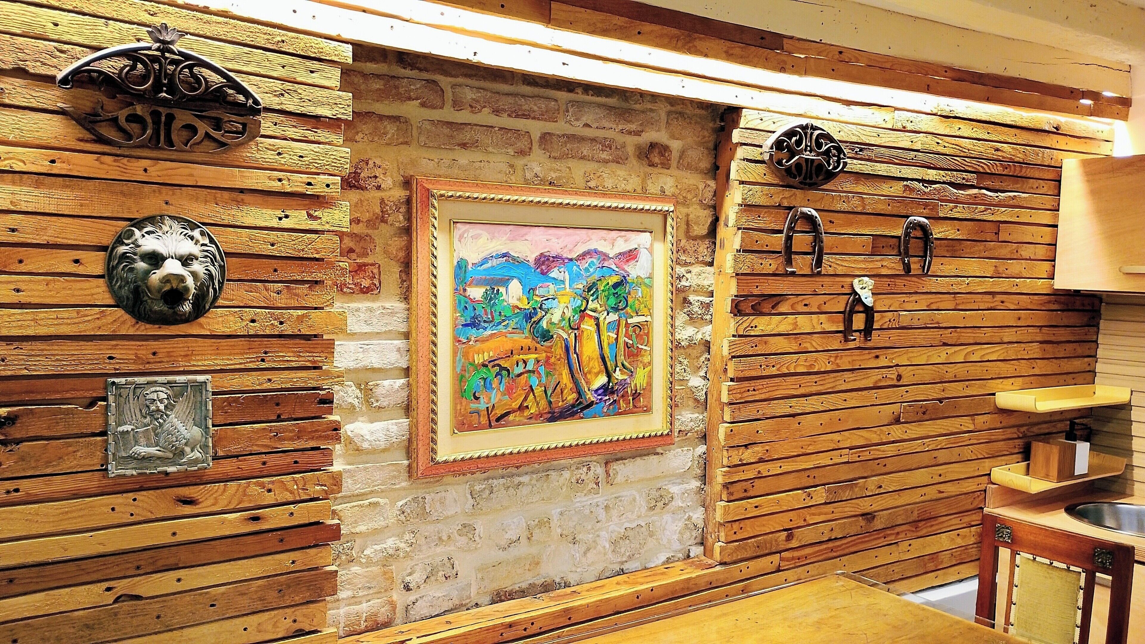 A rustic interior with wooden paneling, a framed painting, and a sink.
