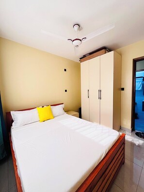 Ein Hotelzimmer mit Bett, Kleiderschrank und Deckenventilator.