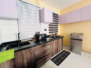 Eine Küche mit Holzausstattung, einer schwarzen Arbeitsplatte, einer Mikrowelle, einem Gasherd und einem Kühlschrank.