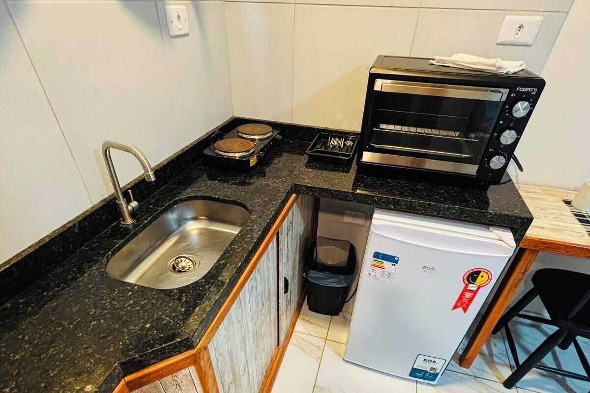 A compact kitchen with a sink, a toaster oven, and a refrigerator.