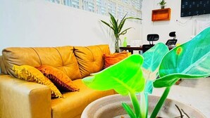 Ein Wohnzimmer mit einer Couch, einer Topfpflanze und einer Wand mit geometrischem Muster.