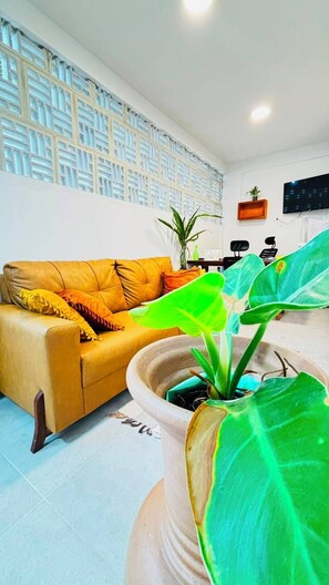 A living room with a sofa, a potted plant, and a wall with a geometric pattern. - Porto Beach Flats Dolce Vita Piscina 03C (Ipojuca)
