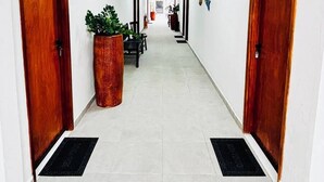 Ein Hotelgang mit zwei Holztüren, einem Blumentopf und einem gefliesten Boden.