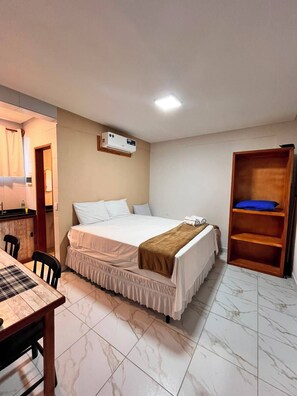 A bedroom with a bed, bedside table, and a wooden shelf unit. - Porto Beach Flats Dolce Vita Piscina 03C (Ipojuca)