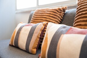 A sofa with striped cushions and a window in the background. - GuestReady - Bright Studio in Bonfim District (Porto)