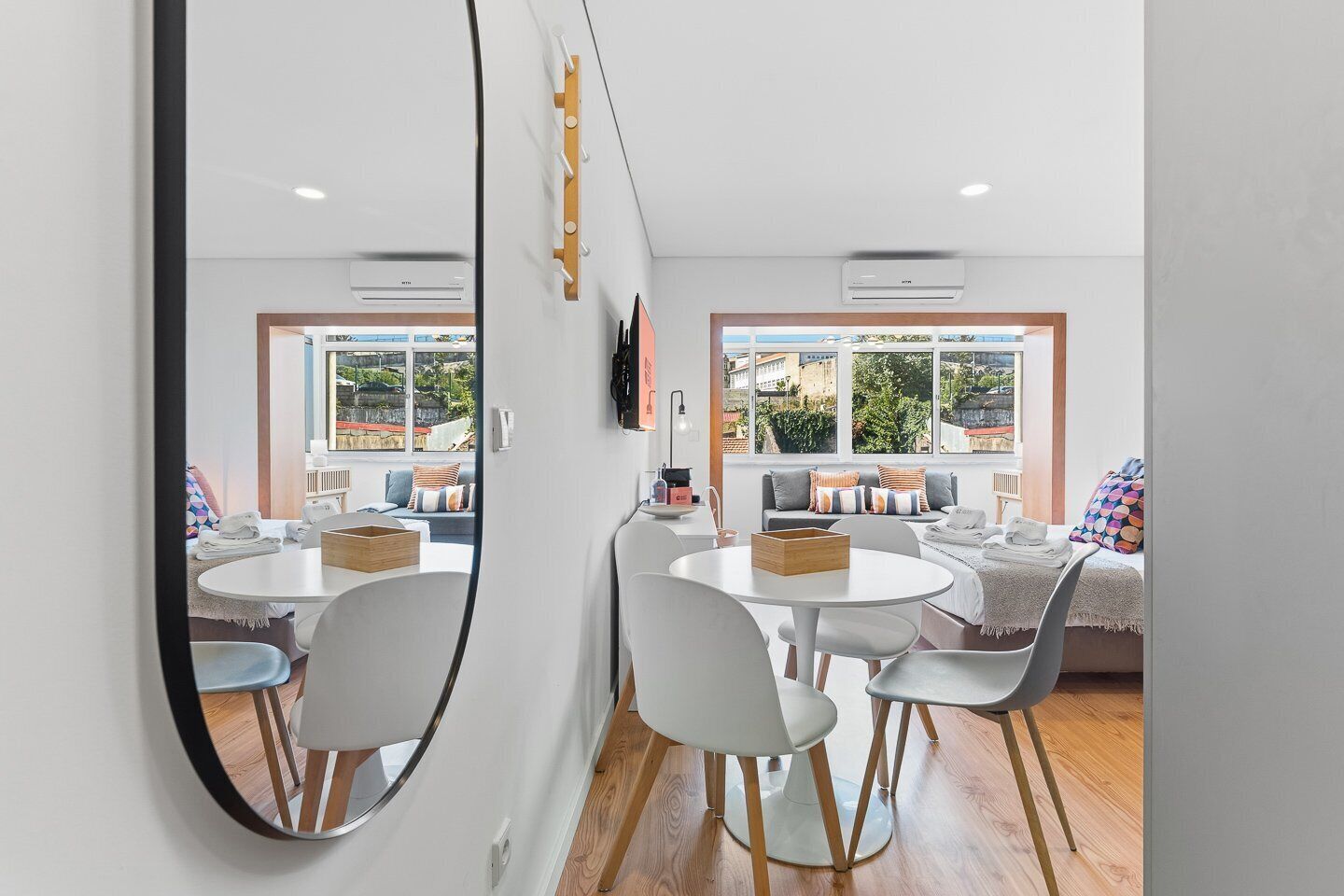 A modern hotel room with a dining area, a large mirror, and a view of the outside.